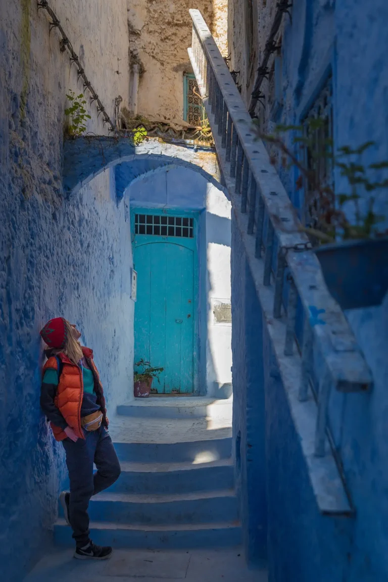 Traveller pausing on a blue-washed stepped lane in the Chefchaouen medina, morning light